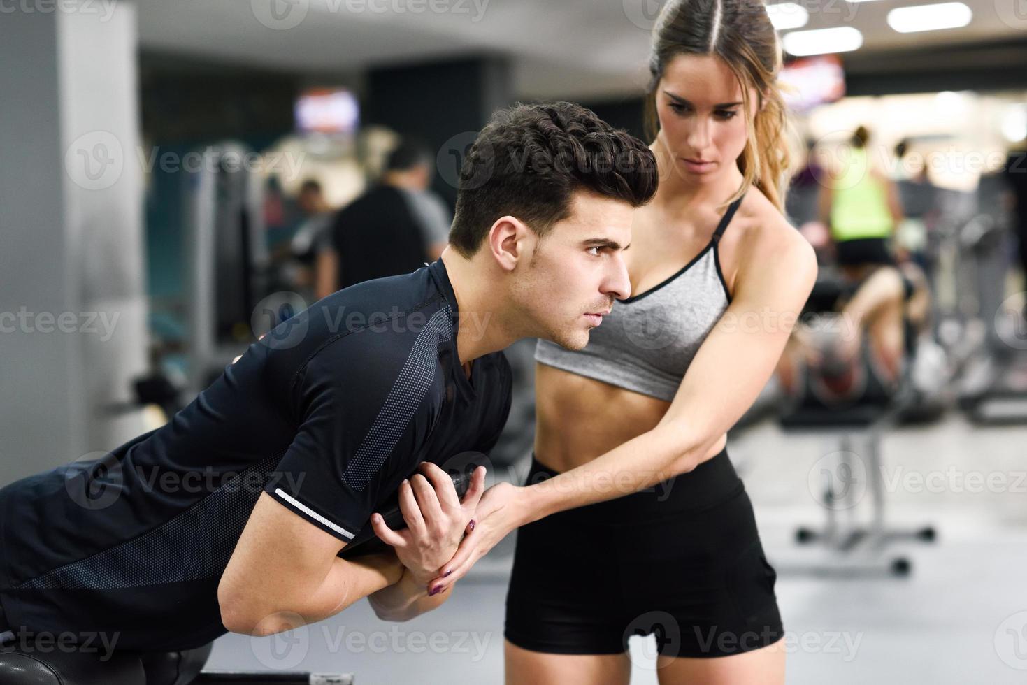 Personal trainer helping a young man lift weights photo