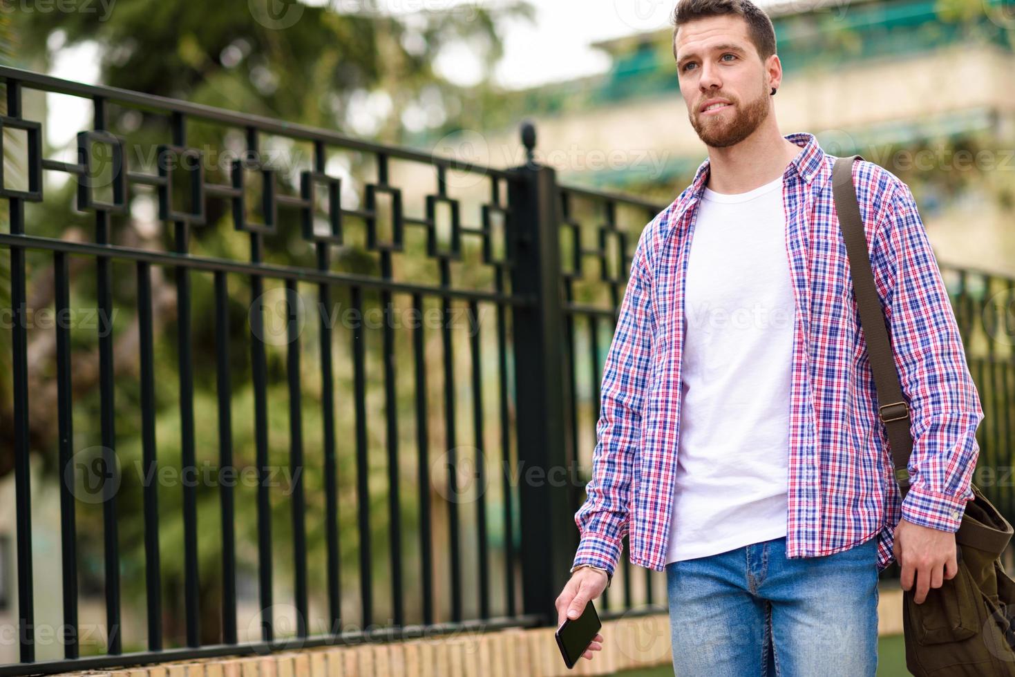 Young bearded man walking in urban background. Lifestyle concept. photo