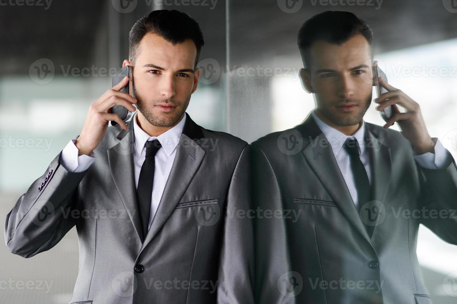 atractivo joven empresario por teléfono en un edificio de oficinas foto
