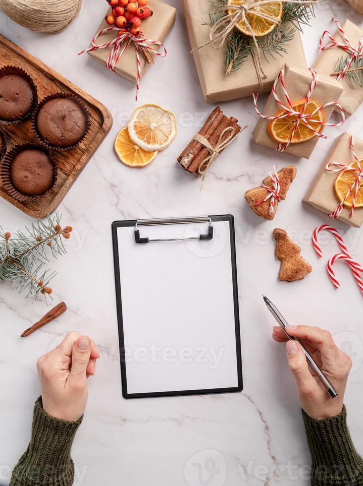 top view hands writing new year goals, resolution or shopping list on a blank paper. Mock up design photo