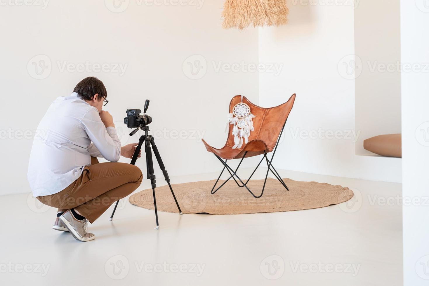 Fotógrafo masculino que trabaja en un interior minimalista, luminoso y aireado, silla, alfombra y almohadas blancas y beige foto