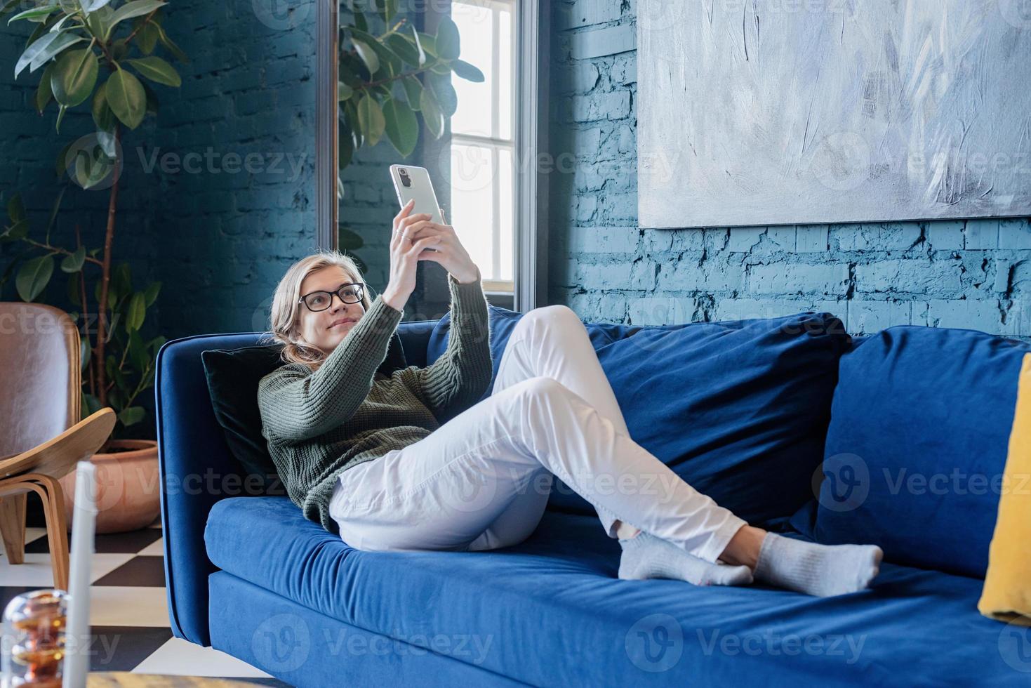 Young woman lying on coach in stylish living room photo