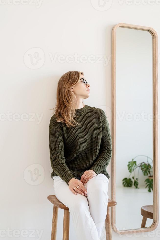 Attractive young woman sitting on the chair in light and airy interior photo