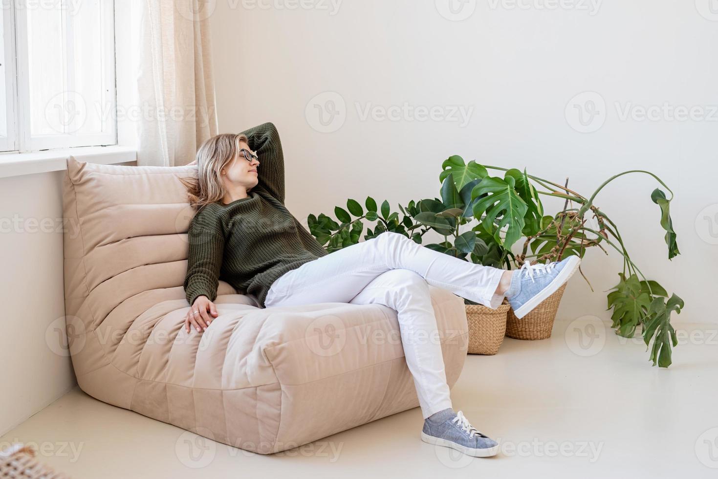 Atractiva mujer joven sentada en la silla en un interior amplio y luminoso con plantas foto