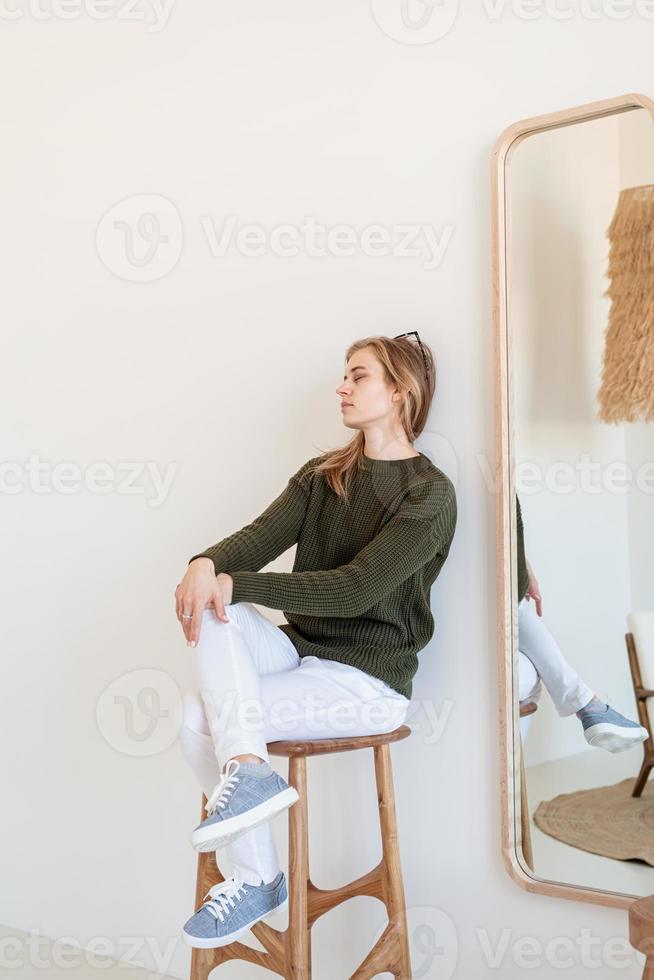 Atractiva mujer joven sentada en la silla en un interior amplio y luminoso foto