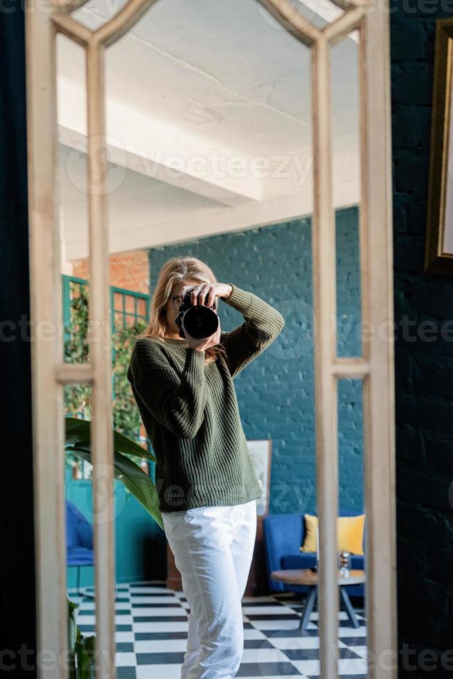 Female photographer taking selfie using camera looking at the mirror photo