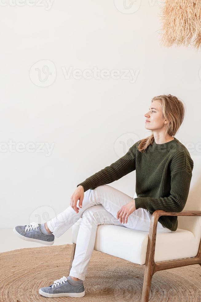 Attractive young woman sitting on the chair in light and airy interior photo