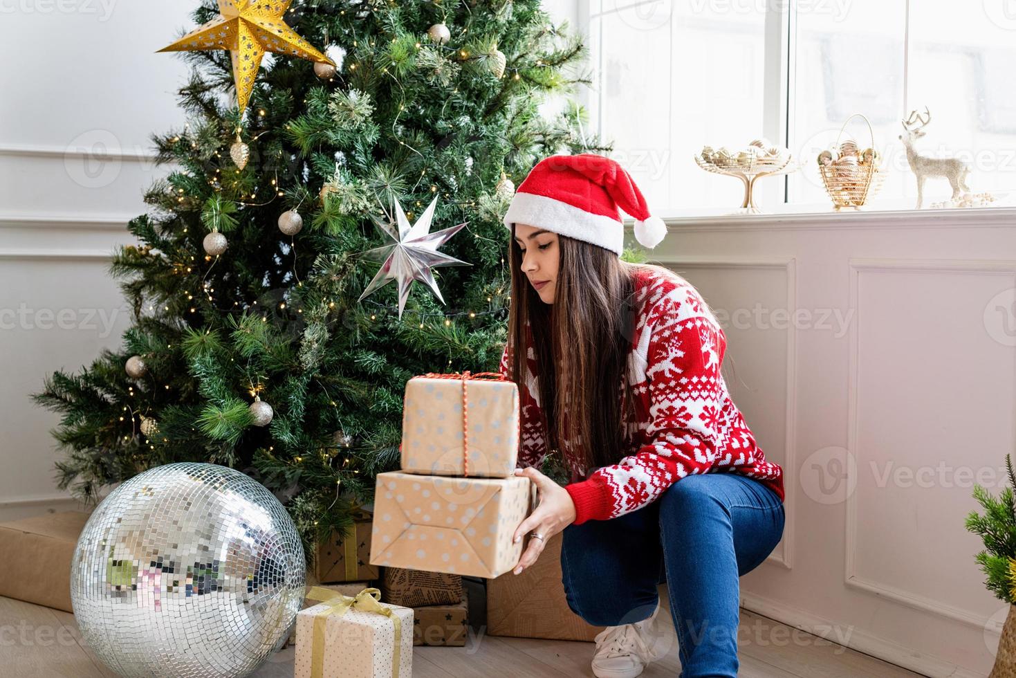 Young woman in red sweater holding a stack of christmas gifts photo