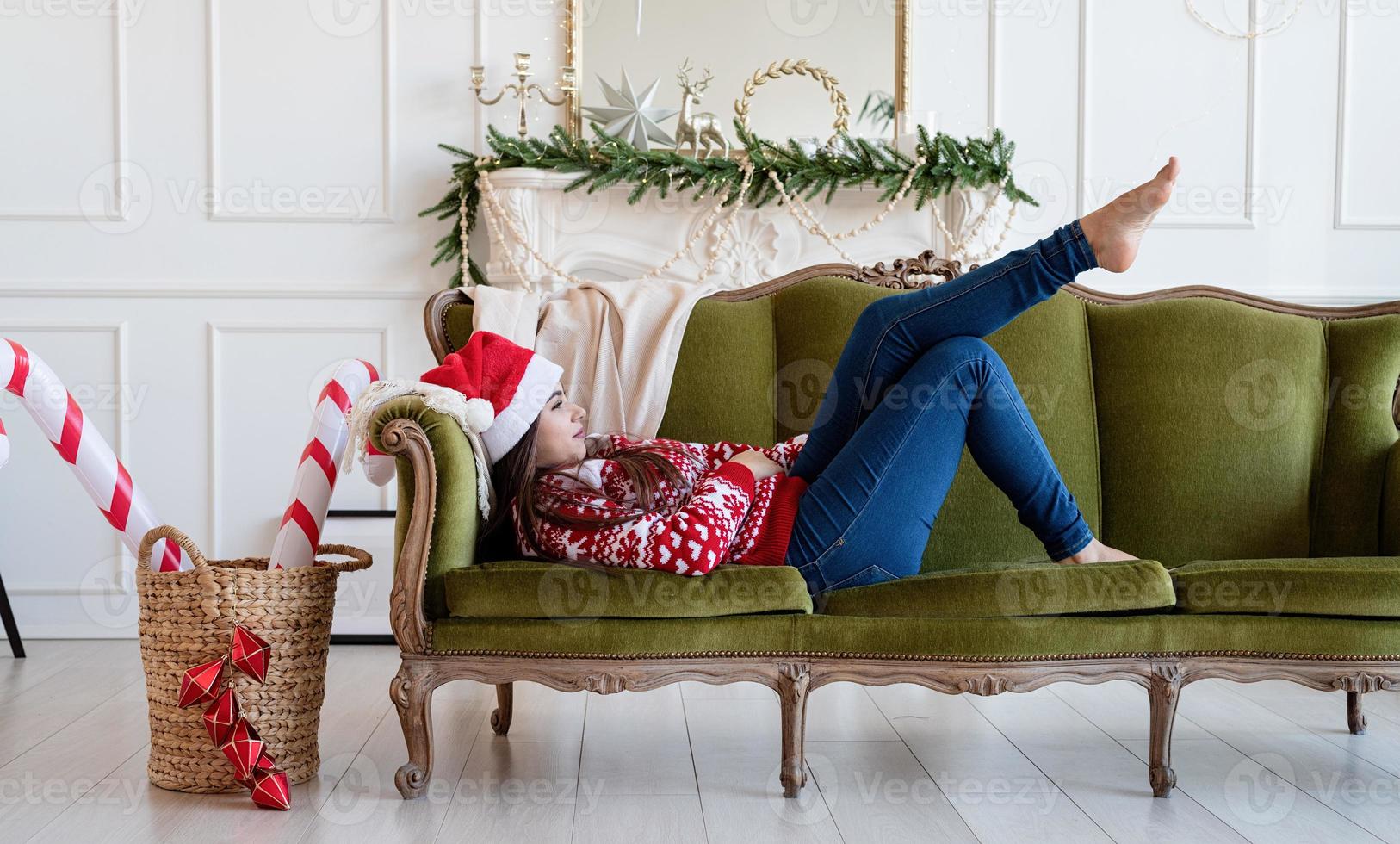 Mujer joven tumbado en el sofá solo en un salón decorado para Navidad foto