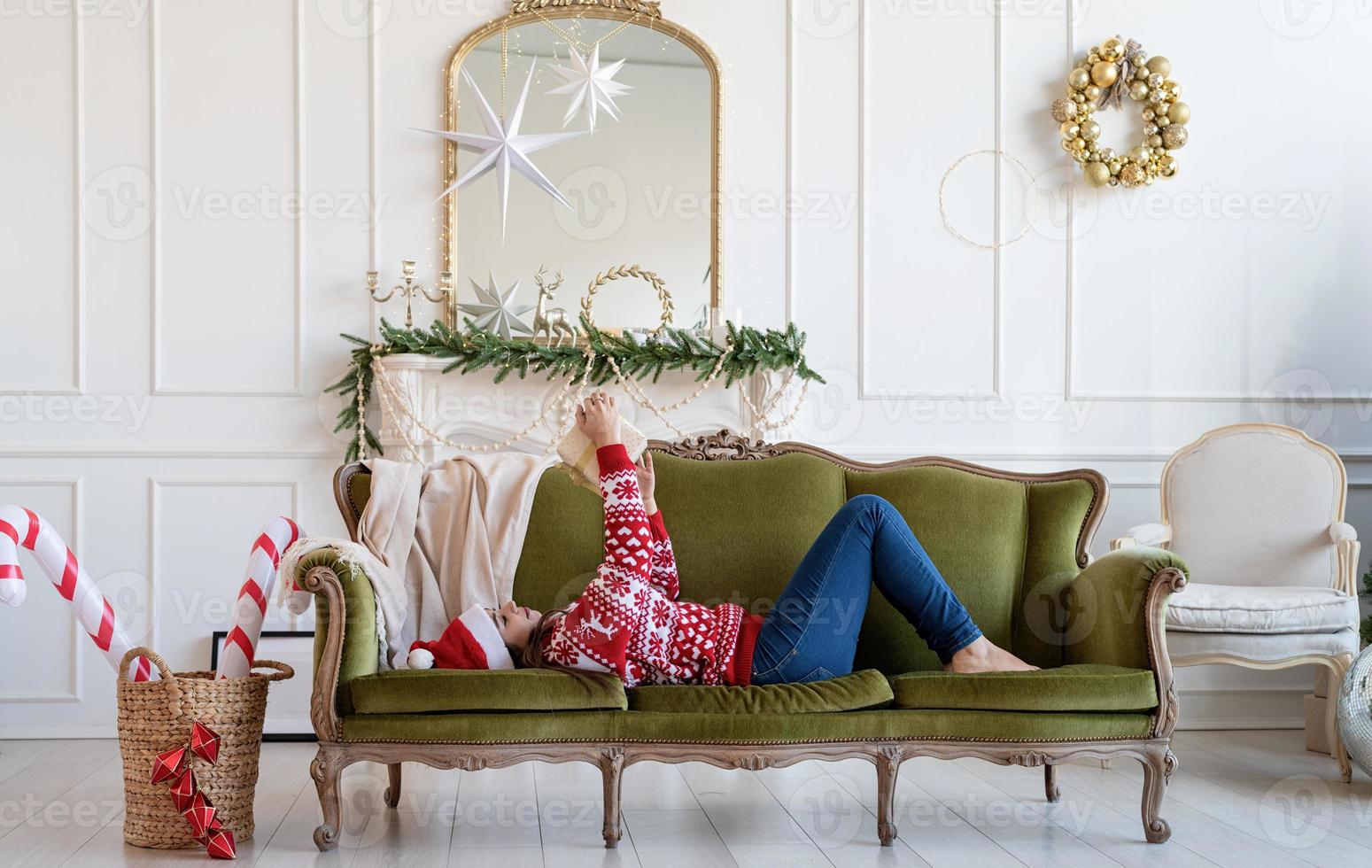 Mujer joven tumbado en el sofá solo en un salón decorado para Navidad foto