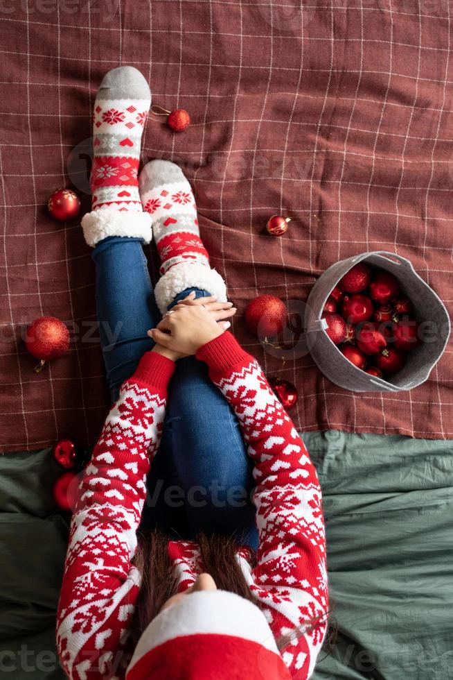 Vista superior de las piernas femeninas con calcetines de navidad en la cama con adornos foto