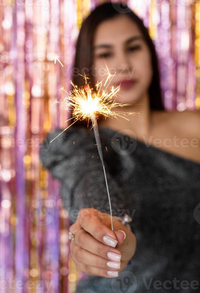 woman in glitter dress holding sparkler, close up hands, romantic look photo