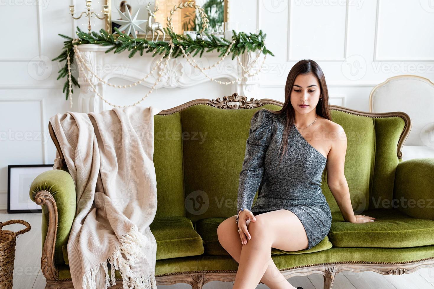 Mujer joven sentada en un sofá en un salón decorado para Navidad foto