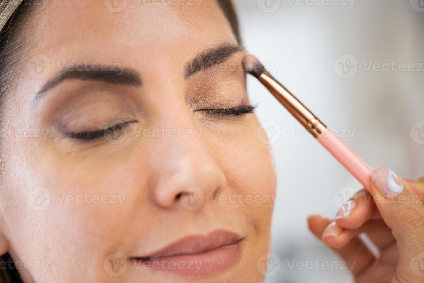 primer plano de una maquilladora que aplica sombra de ojos a su cliente. foto