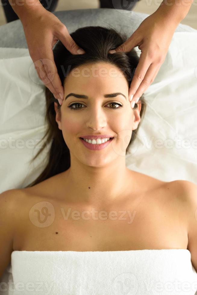 Young smiling woman receiving a head massage in a spa center. photo