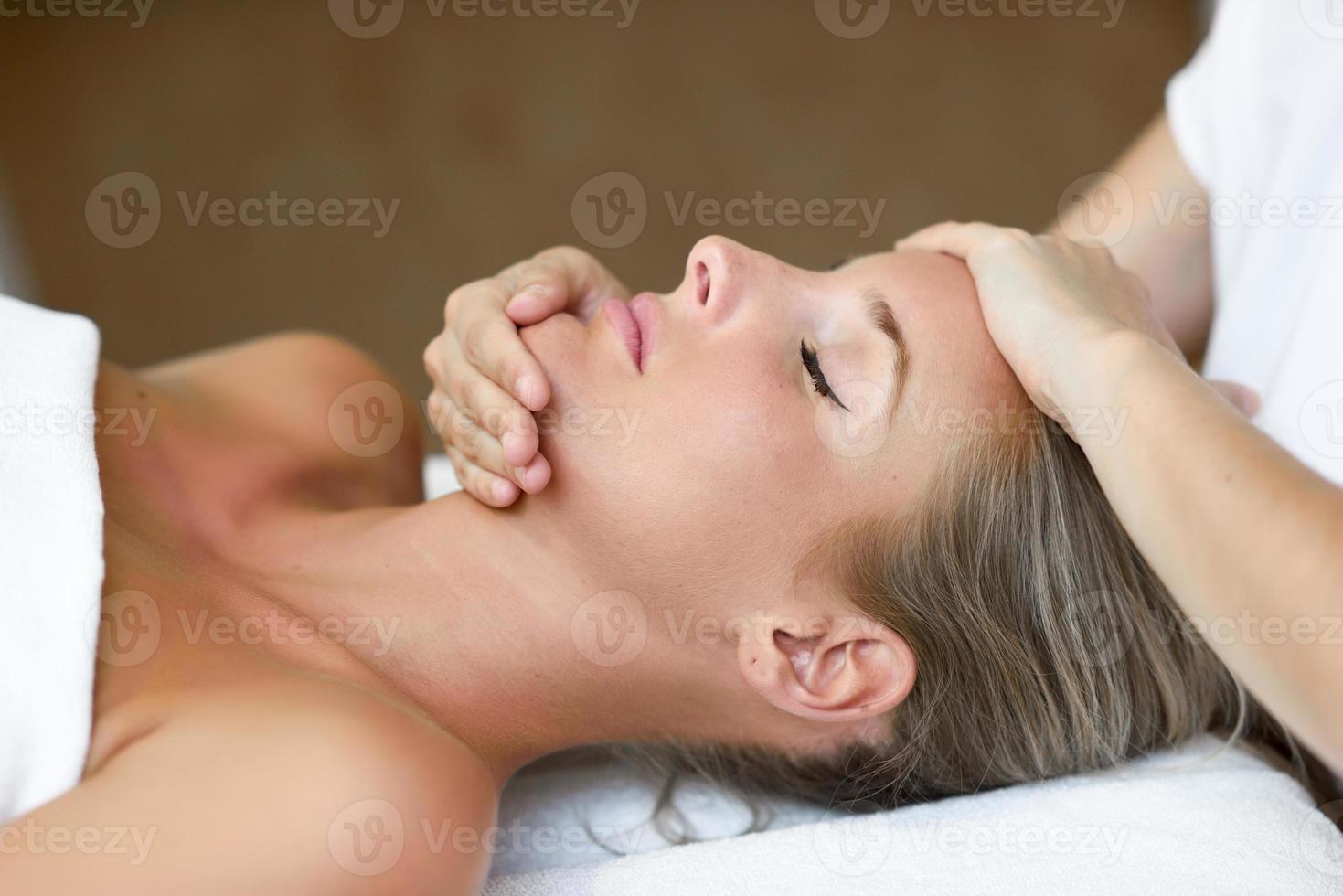 mujer joven recibiendo un masaje de cabeza en un centro de spa. foto