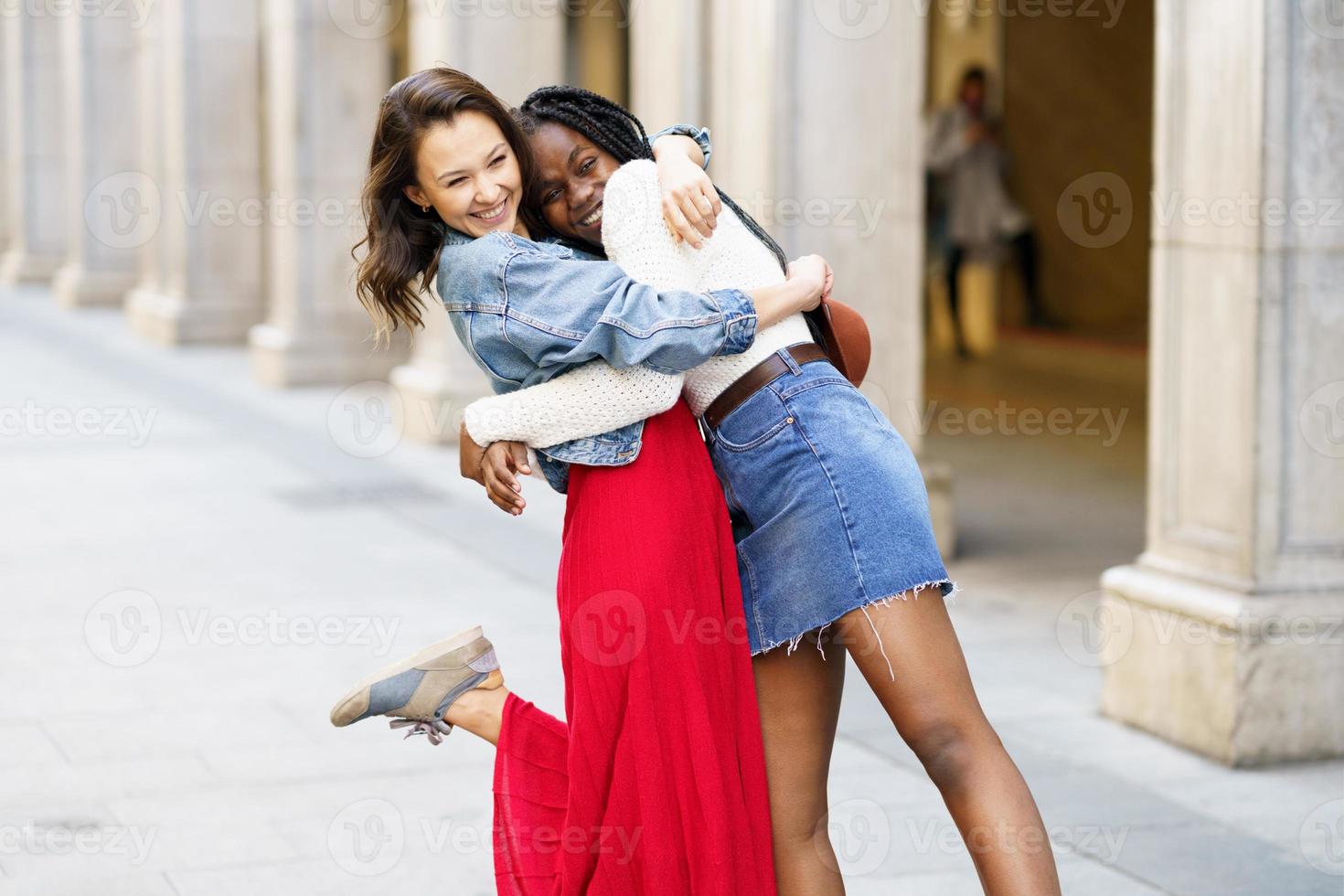Two friends happy to see each other on the street hugging. photo
