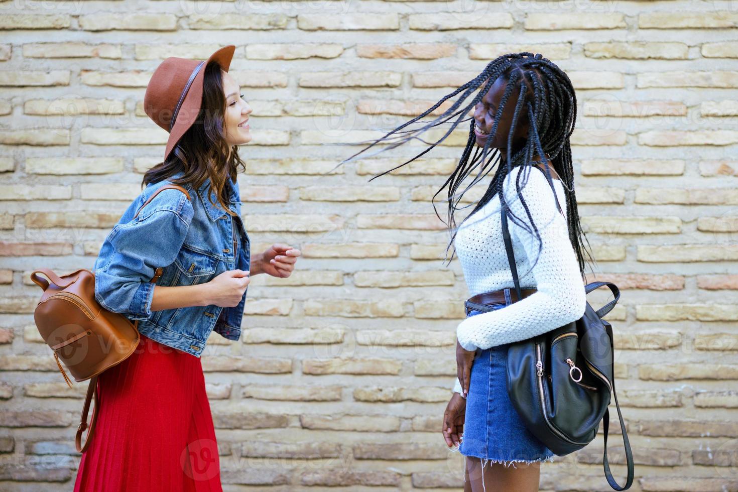 Two female friends having fun together on the street. Multiethnic friends. photo