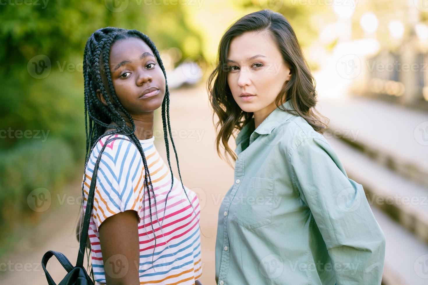 dos mujeres multiétnicas mirando a la cámara juntos en la calle. foto