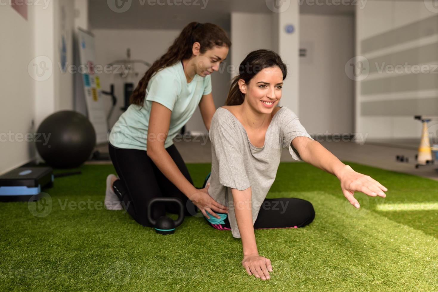 Physical therapist assisting young caucasian woman with exercise photo