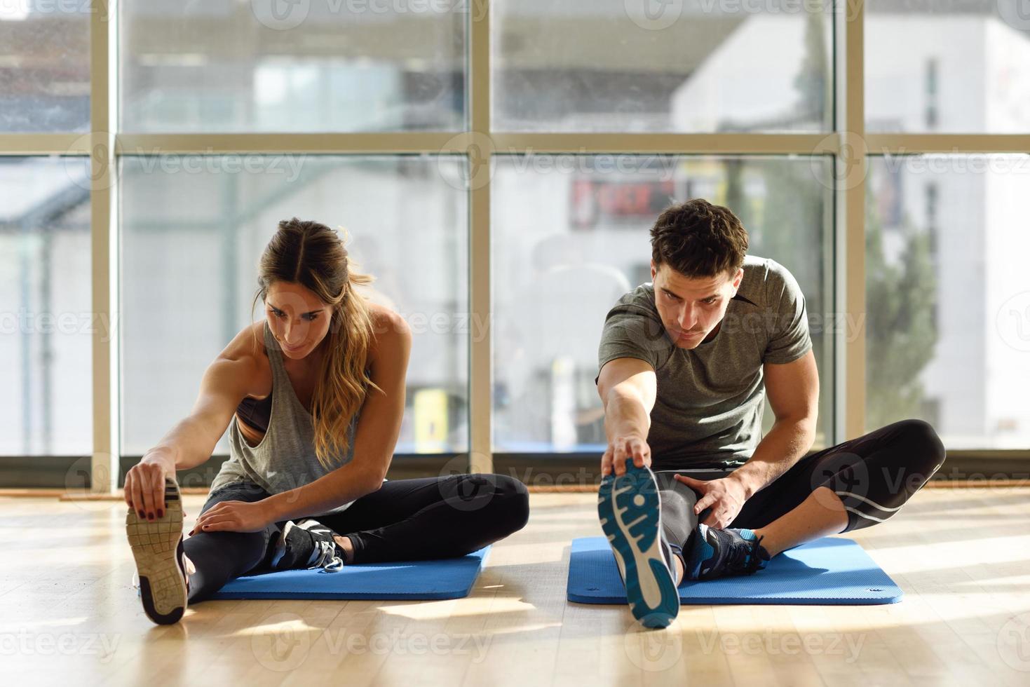 Two people streching their legs in gym. photo