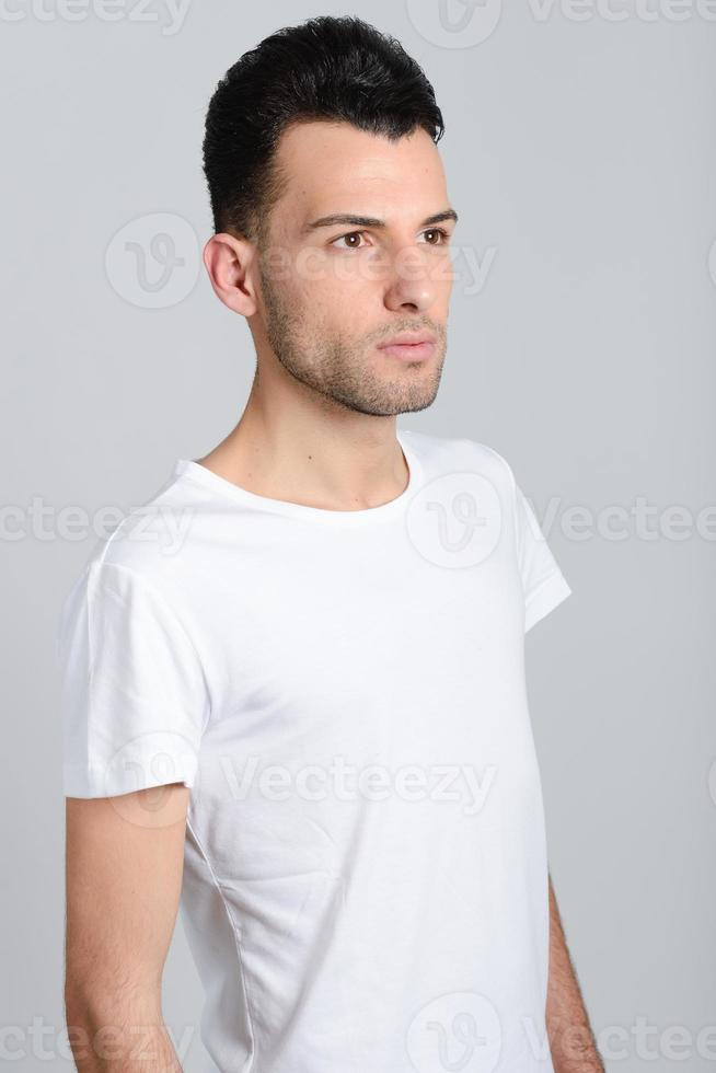 Serious young man standing against white background photo