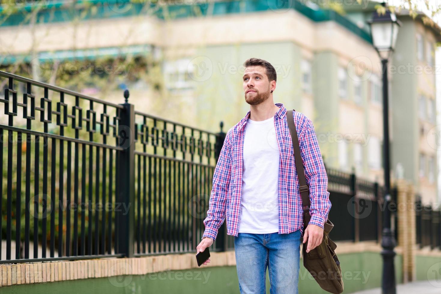 joven barbudo caminando en el fondo urbano. concepto de estilo de vida. foto