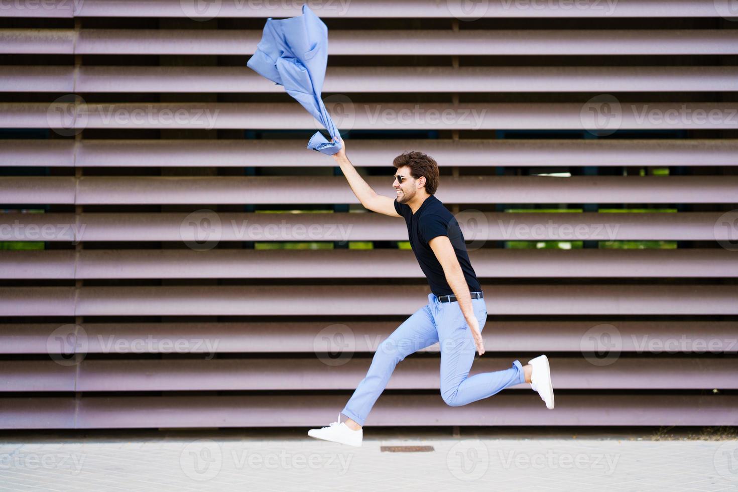 Young man wearing a suit jumping outdoors photo