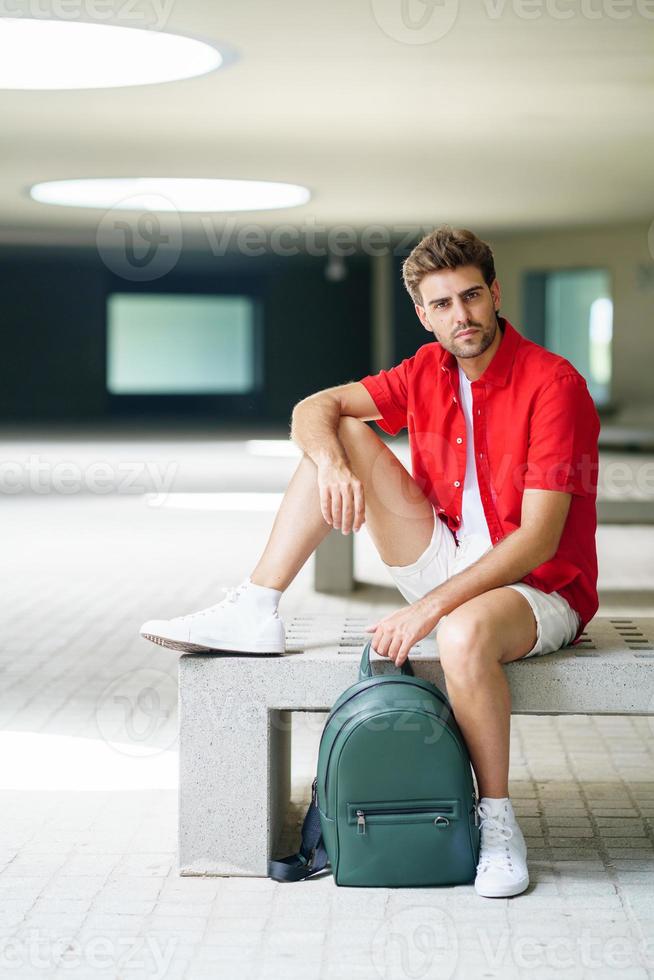 estudiante masculino sentado en un banco del campus universitario foto