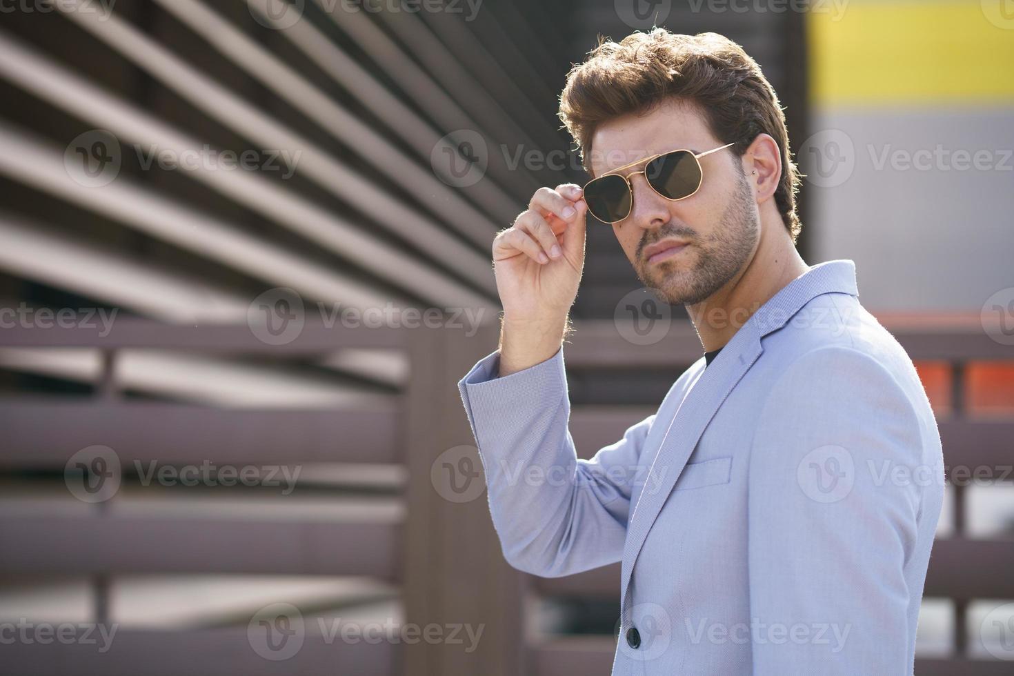 Hombre guapo joven con gafas de sol en el fondo urbano foto