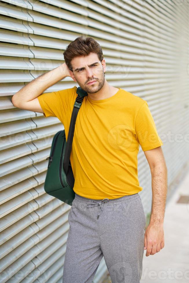 Joven con corte de pelo moderno en el fondo urbano foto