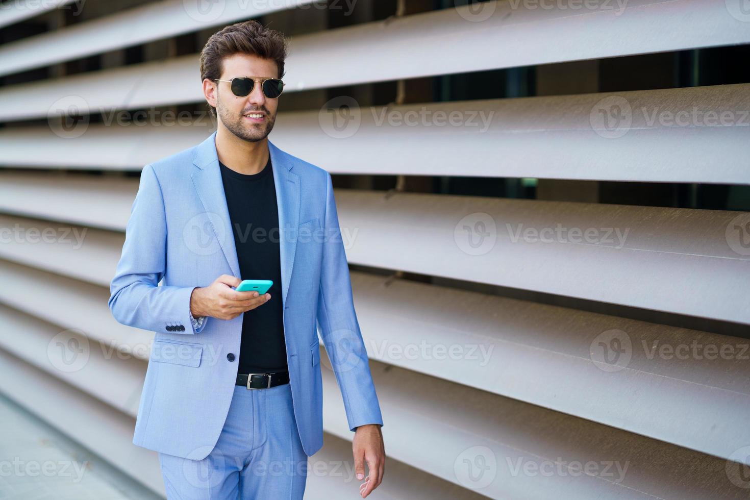 hombre caminando por la calle usando su teléfono inteligente foto