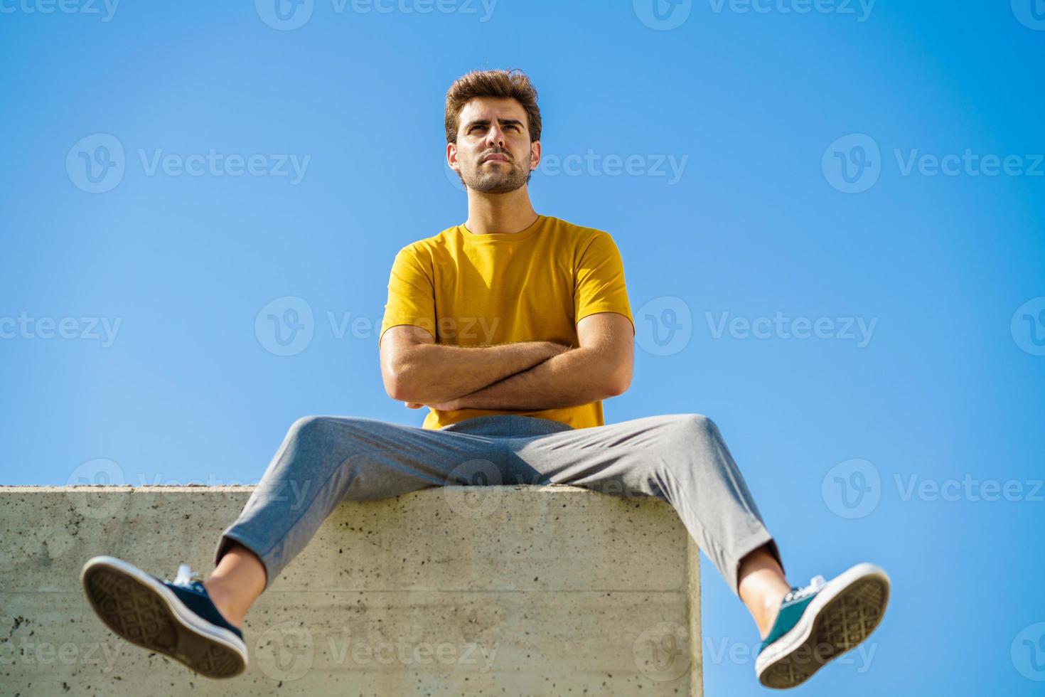 Man sitting on a ledge looking around photo