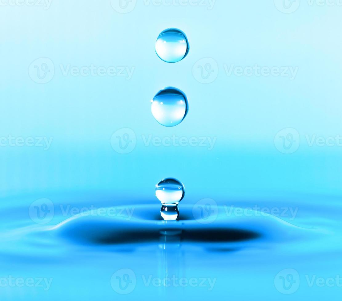 Salpicaduras de gota de agua transparente realista y agua azul coloreada en blanco. foto