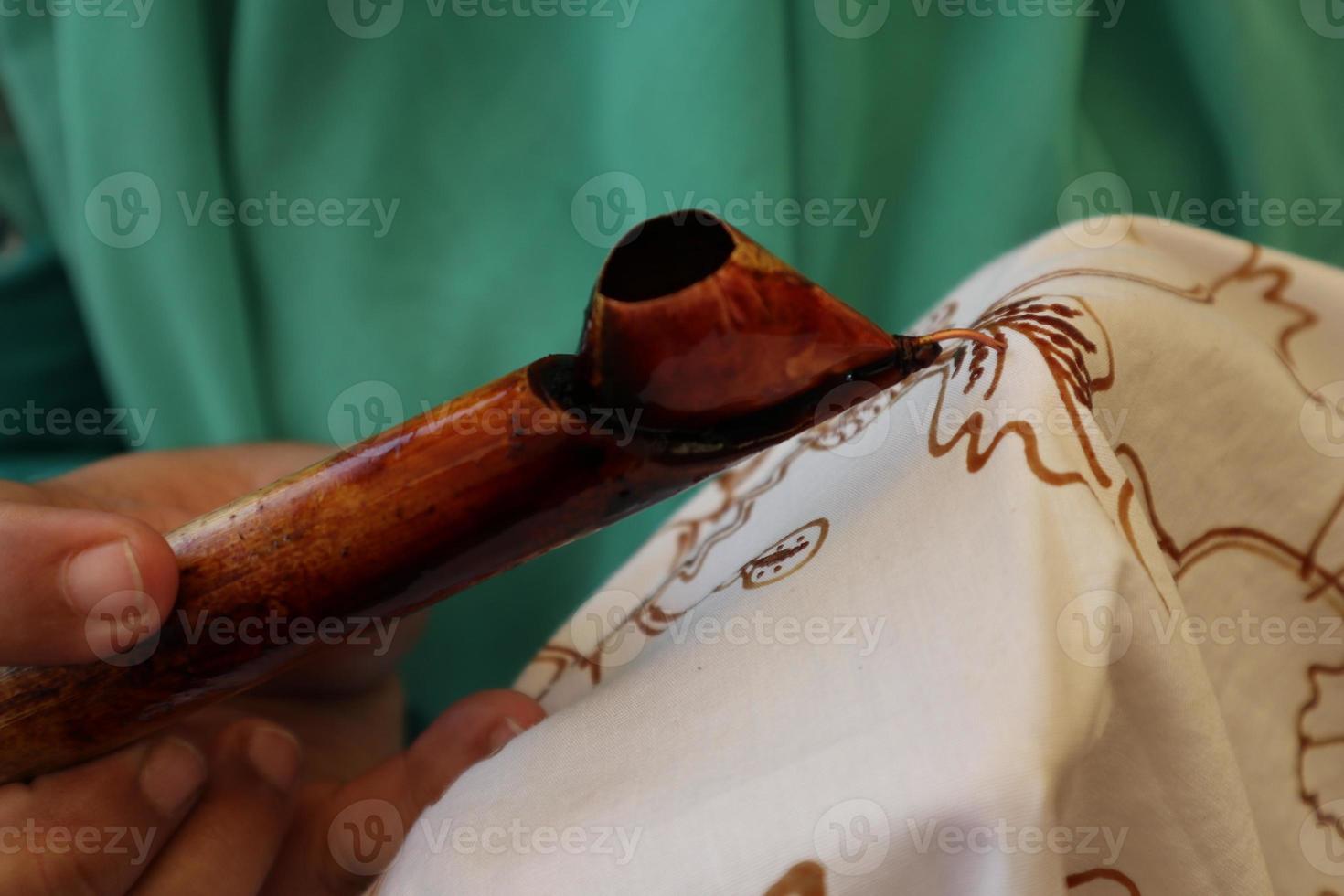 Close Up hand to make batik tulis on the fabric with canting photo