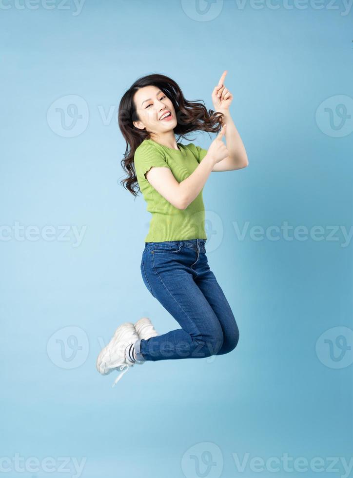 Retrato de una hermosa joven asiática saltando, aislado sobre fondo azul. foto