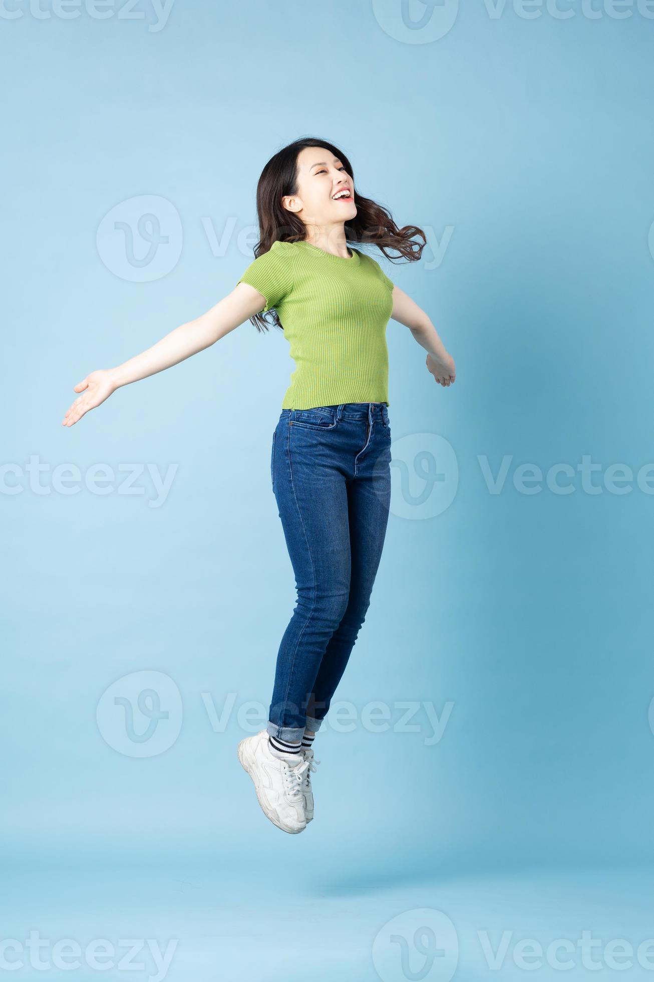 Portrait of beautiful young asian girl jumping up, isolated on