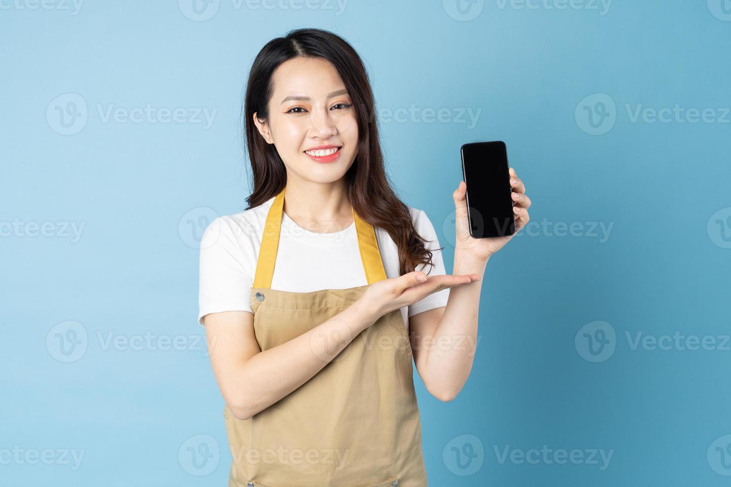 Asian female waitress portrait, isolated on blue background photo