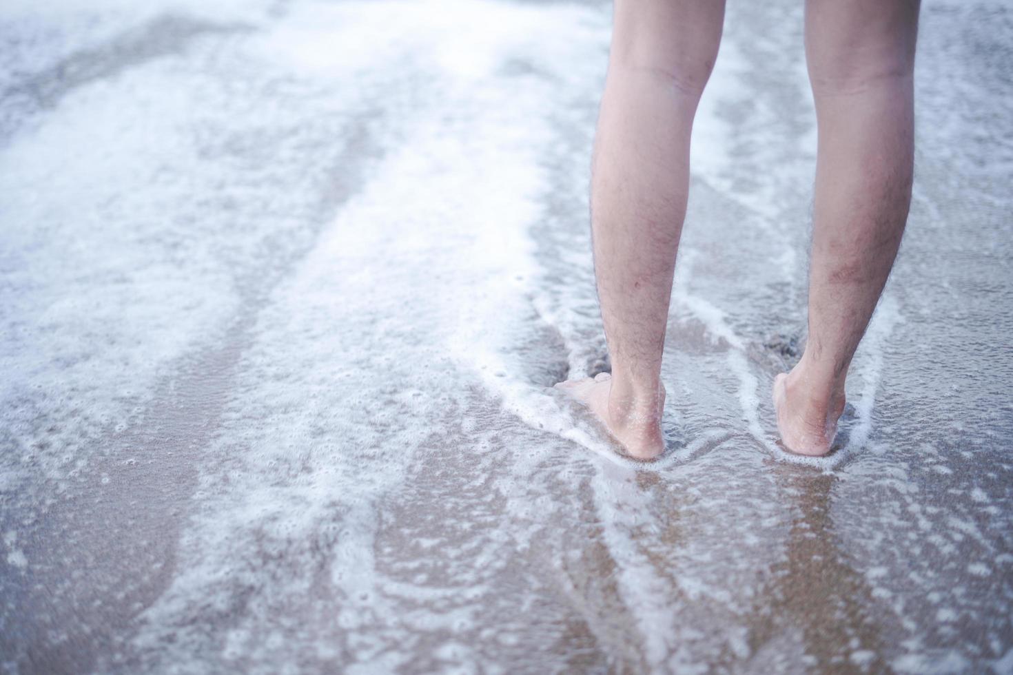 disfruta del suave batir de las olas de espuma con los pies descalzos. Vaya a la playa para disfrutar del tiempo de vacaciones relajándose en el agua del mar y las playas de arena. foto