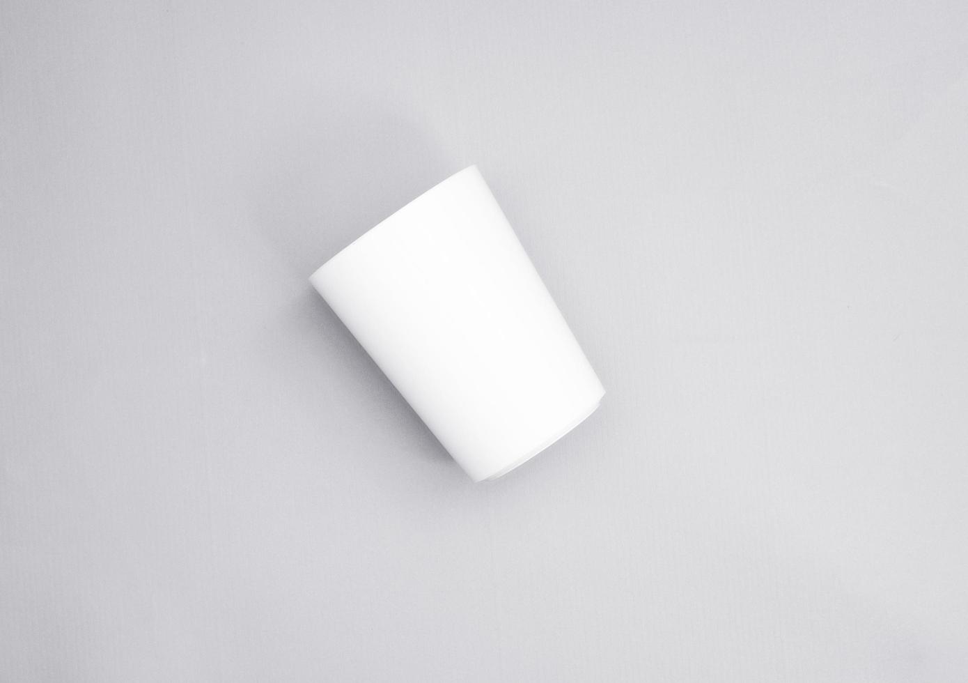 a cup in oblique position from top point of view. minimal shot for simple mockup. white plastic cup on grey background. realistic mockup for promotion. photo