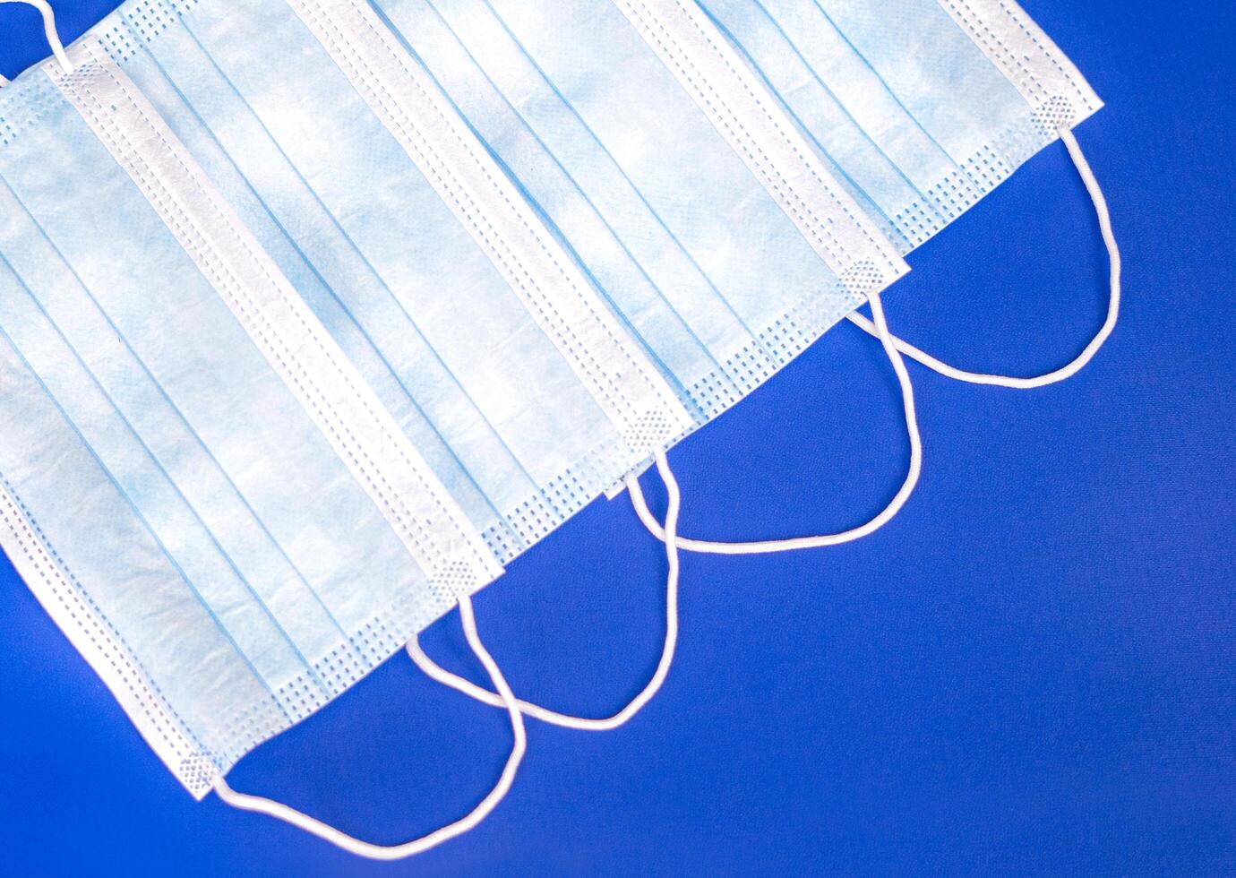 four disposable masks in blue color on a blue background. essential equipment for going outdoor in a pandemic situation. photo