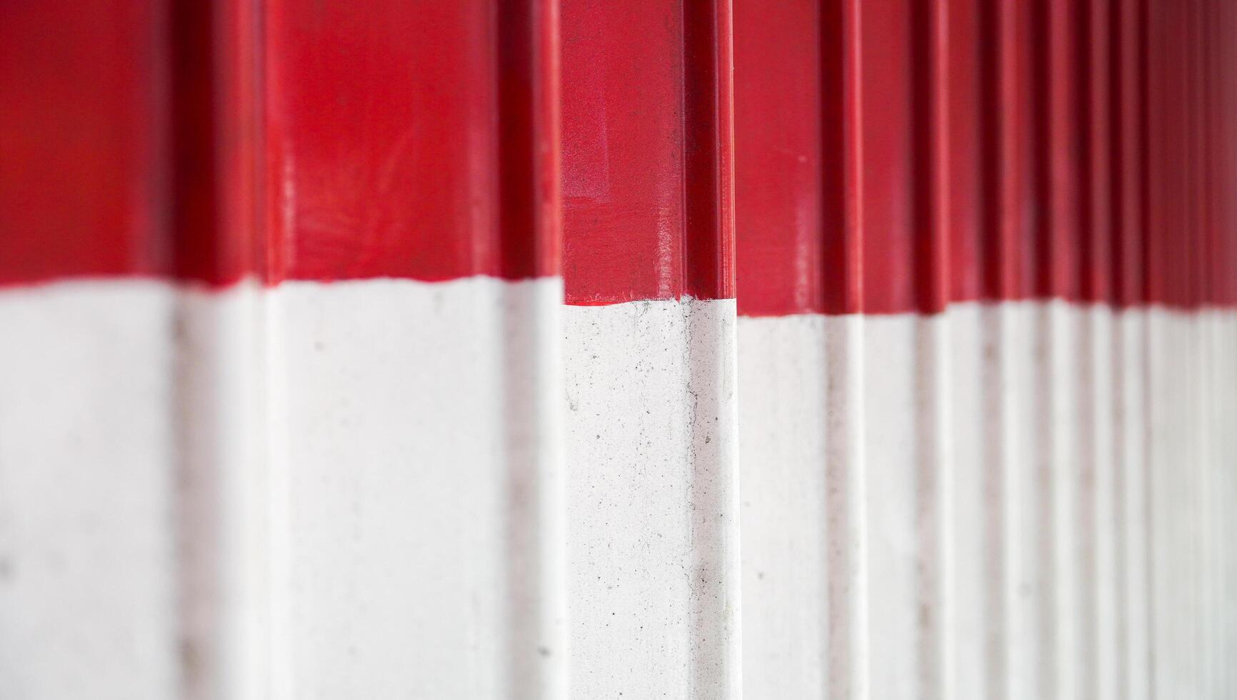 el aspecto detallado de la puerta plegable roja y blanca. la vista en primer plano de la tienda cerrada mediante una puerta plegada. el fondo texturizado del material de la calle. foto