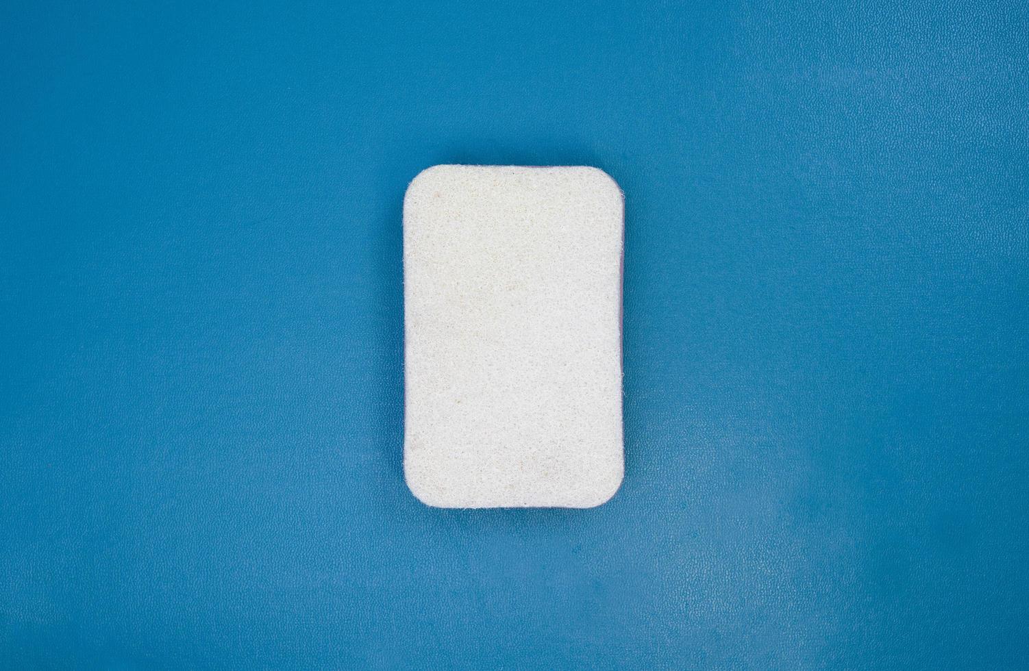 white melamine sponge on blue background. household cleaning tool for daily use. dishwashing accessory at home. photo