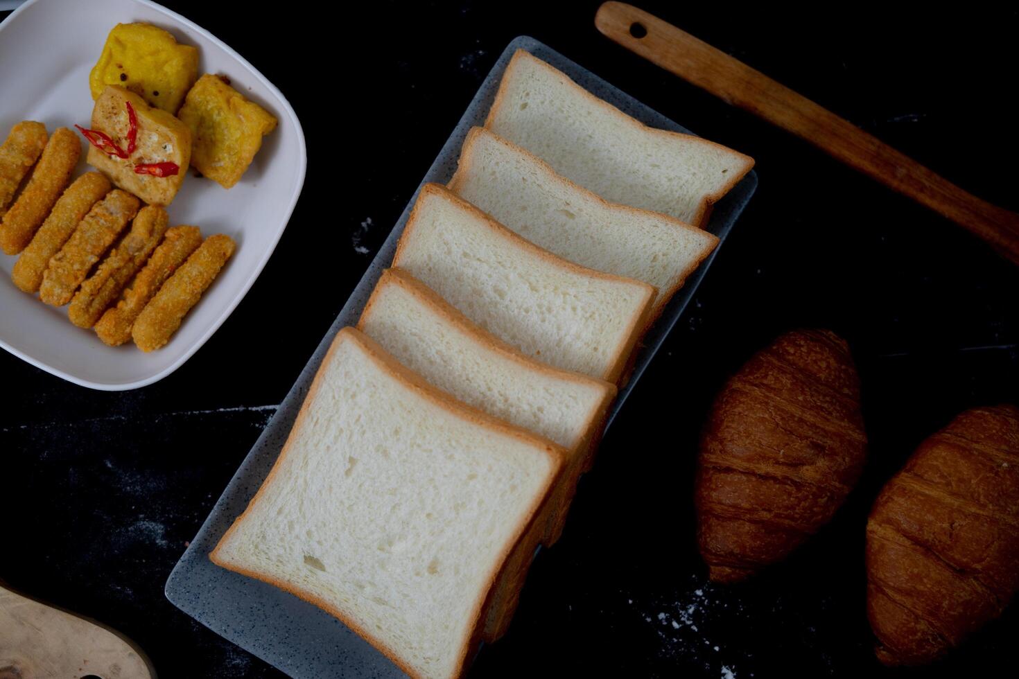 the sliced white bread, nugget, and croissant on black. a shoot for photo presentation or advertisement.