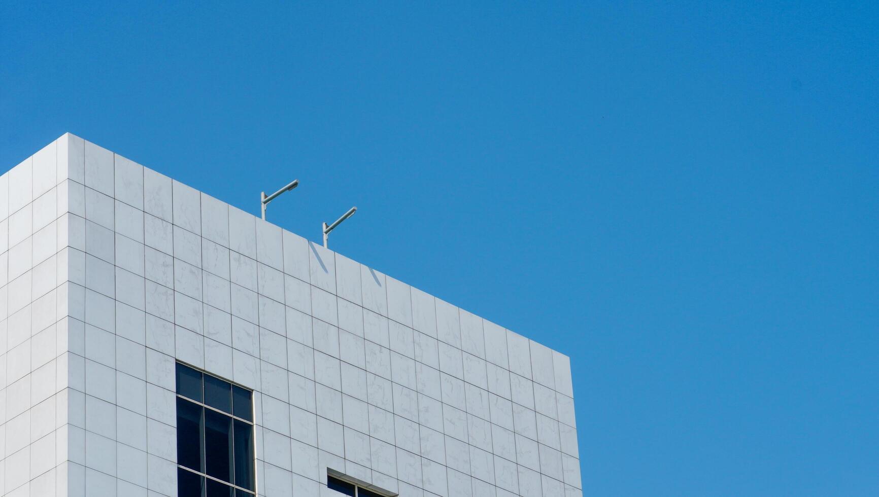 a skyscraper building that has a white ceramic wall with a blue sky background. the high building in the urban area. photo