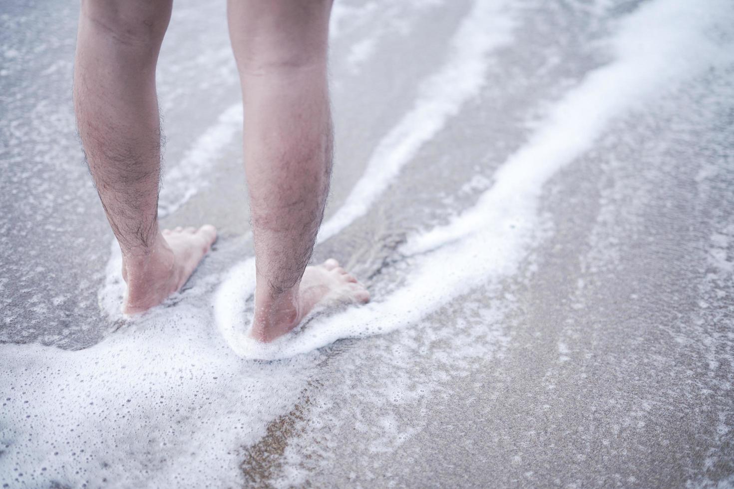 disfruta del suave batir de las olas de espuma con los pies descalzos. Vaya a la playa para disfrutar del tiempo de vacaciones relajándose en el agua del mar y las playas de arena. foto