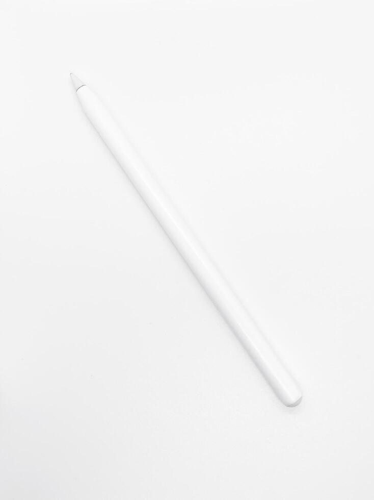 white stylus pen on a white background. a pen to draw or create something on tablet or phone. creating illustration as it's on paper using modern technology. photo