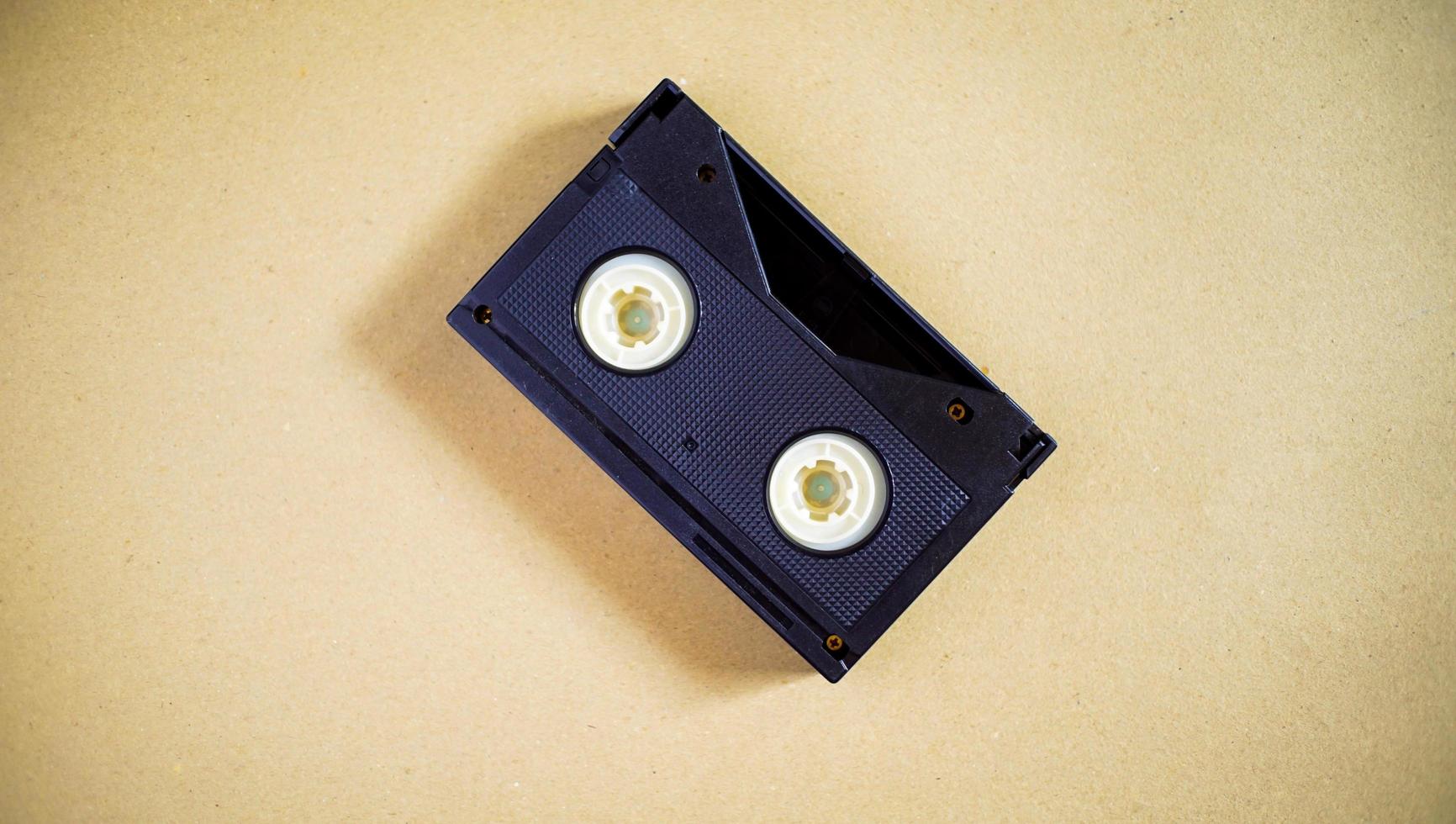 una vieja cinta de audio que fue popular en el pasado. un casete negro sobre un escritorio beige. un material viejo en buen estado. foto