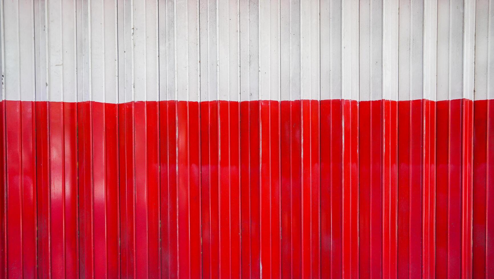 el aspecto detallado de la puerta plegable roja y blanca. la vista en primer plano de la tienda cerrada mediante una puerta plegada. el fondo texturizado del material de la calle. foto