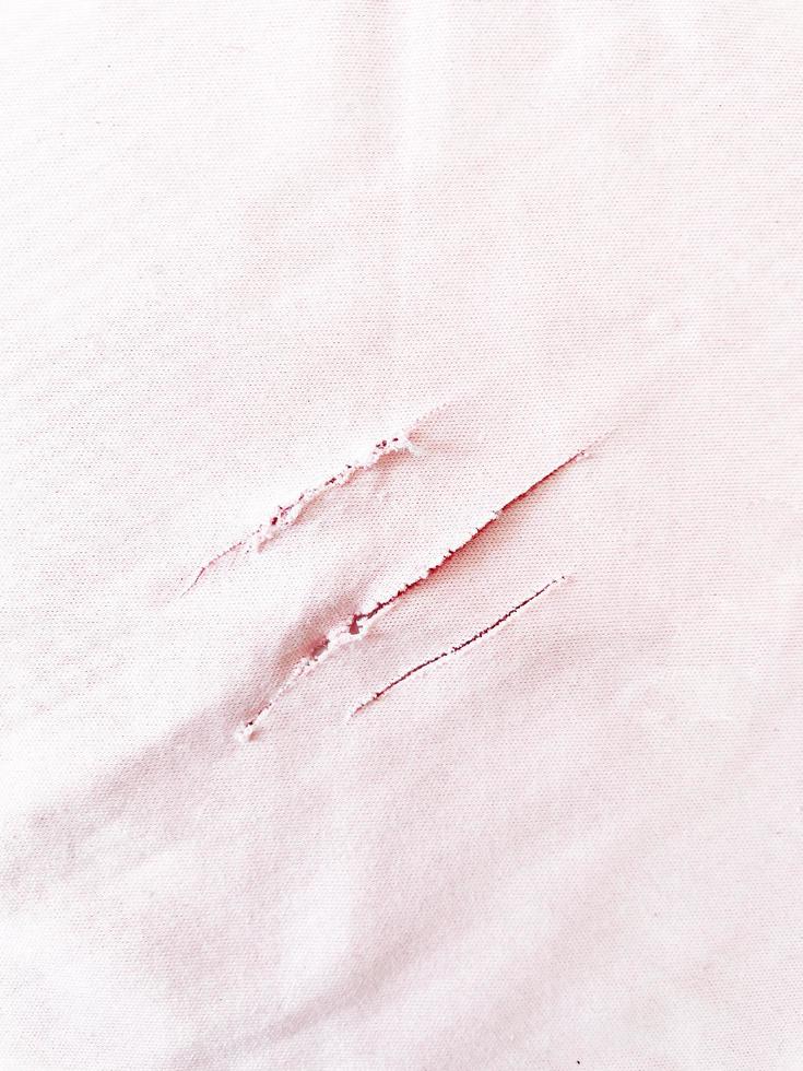 rip fabric in pink. torn textured material. a close-up shot of a shred textile. the unique claw marks on cotton material. baby pink color. photo